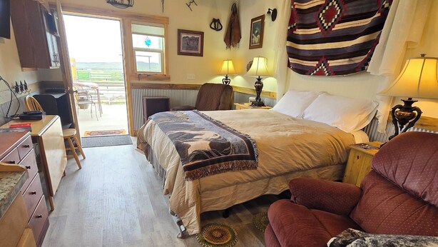 Une pièce confortable avec un lit, un canapé rouge, un plafond en bois et une vue sur l’extérieur.