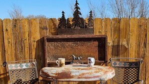 Une terrasse extérieure avec une table ronde et deux chaises, un barbecue et des éléments de décoration.