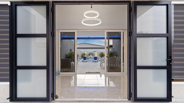 L’entrée d’un hôtel, avec une porte en verre, donnant sur un espace piscine.