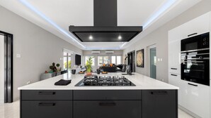 Une cuisine moderne dotée d’un îlot central, de meubles de rangement noirs et d’appareils électroménagers intégrés.