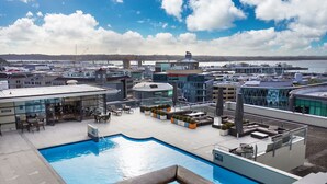 A rooftop pool area with a view of the marina and buildings in the background. - Urban Retreat in the Heritage Building (Auckland)