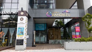A modern building with a sign for 'Grand Bleu' and another for 'Banh Mi Sai G'. - Grandbleu Hotel & Residence (Incheon)