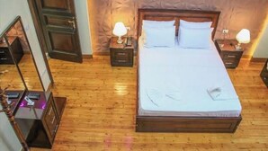 A neatly made bed with white linens, two bedside tables with lamps, and a wooden floor. - City center hotel Cairo  (Cairo)