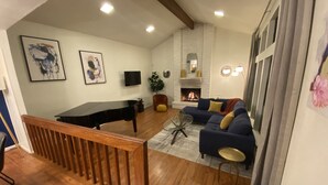 Sala de estar com piano, sofá e lareira.