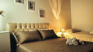 A hotel room with a large bed, a bedside table, a lamp, and two framed pictures on the wall. - News Hospedagem  (Paraty)
