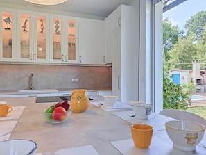 Una cocina moderna con armarios blancos, un ventanal y vistas al exterior.