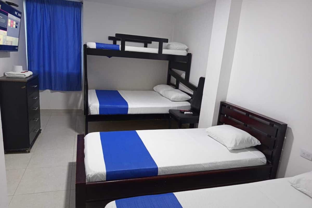 A dormitory room with bunk beds, a desk, and a chair.
