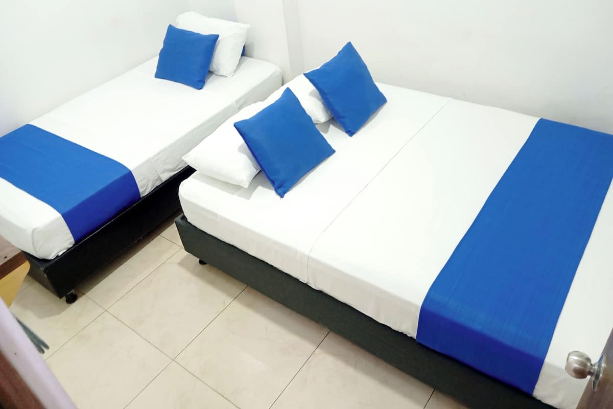 Two single beds with blue and white bedding, a black headboard, and a tiled floor.