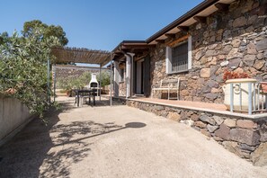 A stone building with a patio, outdoor furniture, and a pergola.