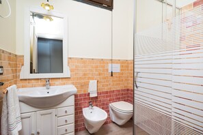 A bathroom with a sink, bidet, toilet, and a mirror.