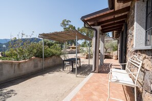 A patio with a table and chairs, a pergola, and a stone wall.