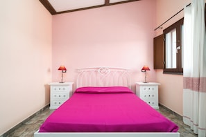 A bedroom with a bed, two bedside tables, a window with curtains, and a door. - Holiday Home 'Casa Stella' with Lake View, Wi-Fi and Air Conditioning (Dorgali)