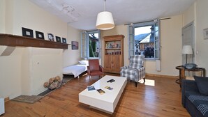 A living room with a white coffee table, a brown leather chair, a plaid armchair, and a bookshelf. - Characterful House in Arreau – Mountain View, Balcony, WiFi, Free Parking, 6 Guests, Pets Welcome (Arreau)