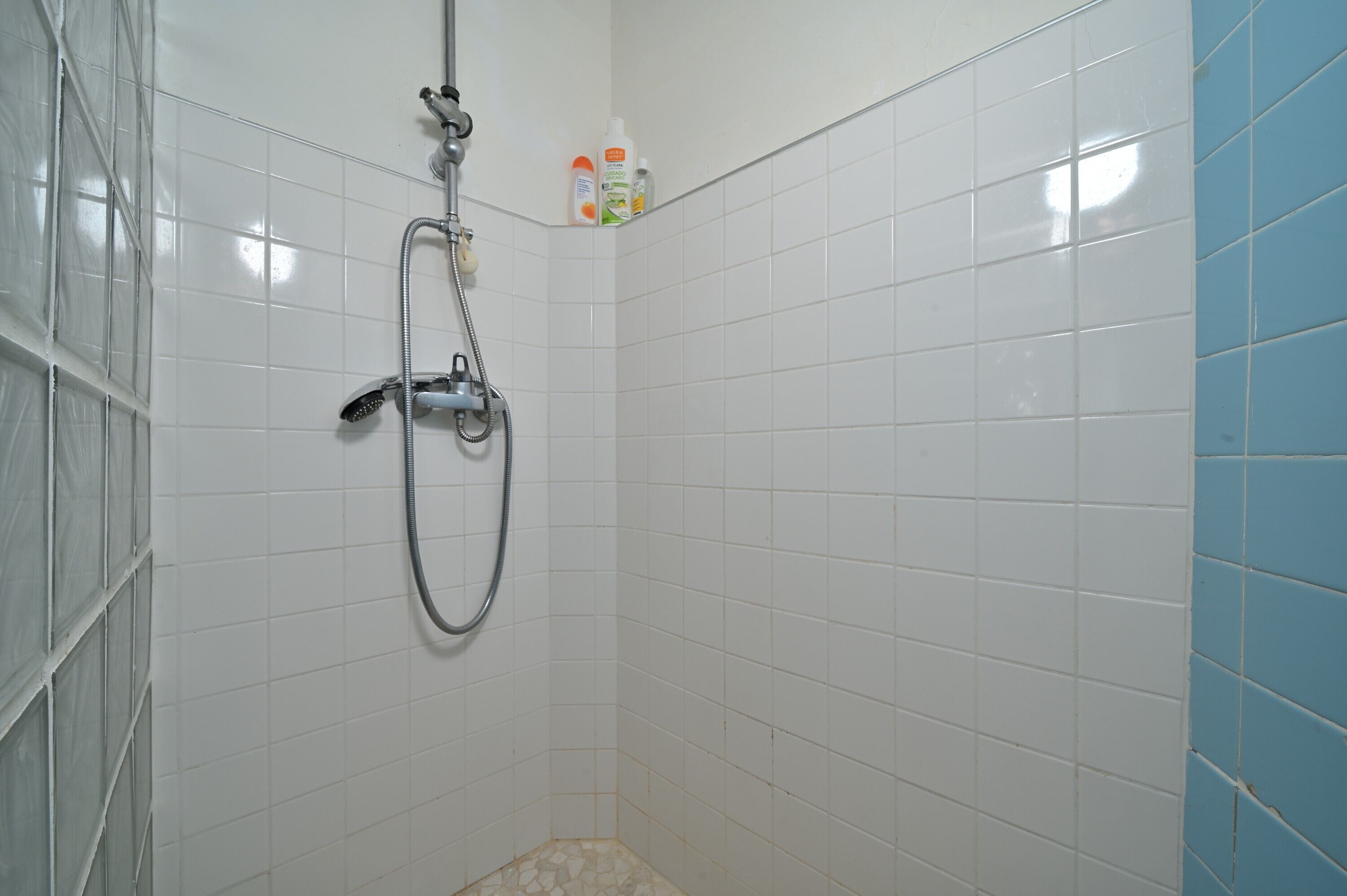 Eine Dusche mit Handbrause und am Wand montiertem Wasserhahn.