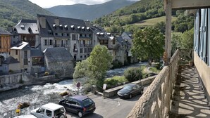A riverside town with historic buildings, a bridge, and a car parked on the street. - Characterful House in Arreau – Mountain View, Balcony, WiFi, Free Parking, 6 Guests, Pets Welcome (Arreau)