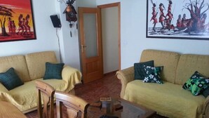 A living room with two sofas, a wooden chair, a glass coffee table, and a door leading to another room. - Apartment 'Residencia Lucia' with Sea View, Wi-Fi and Air Conditioning (Guardamar del segura)