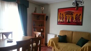 A dining area with a table and chairs, a bookshelf, a sofa, and a painting on the wall. - Apartment 'Residencia Lucia' with Sea View, Wi-Fi and Air Conditioning (Guardamar del segura)