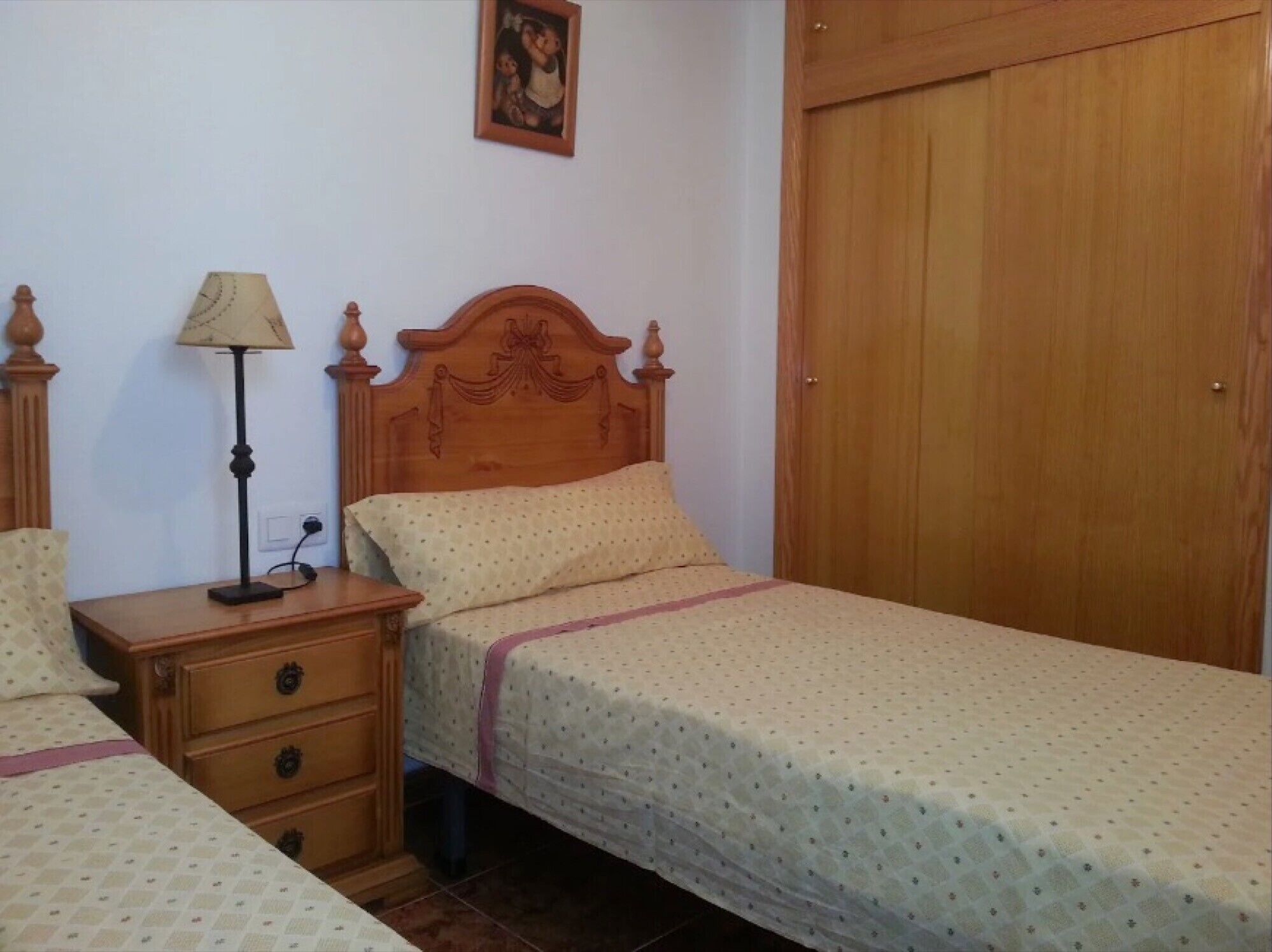 Une chambre à coucher avec un lit en bois, une table de chevet avec une lampe, une commode et une armoire en bois.