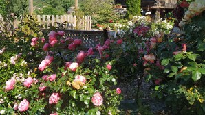 A garden with roses, a wooden pergola, and a rustic building with a tiled roof. - Holiday Home 'El Pedrueco Turismo Rural' with Mountain View, Shared Pool and Wi-Fi (Nava)