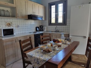 A kitchen with wooden cabinets, a microwave, a stove, a sink, and a dining table with chairs.