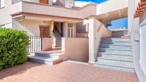 A multi-level residential building with a staircase, a covered entrance, and a satellite dish. - Apartment 'Casa Sara Lu Bagnu' with Private Terrace and Balcony (Lu Bagnu)