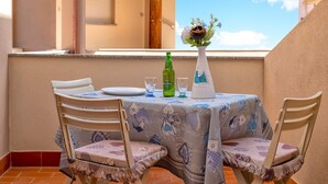 A balcony with a table set for two, a green bottle, and a vase with flowers. - Apartment 'Casa Sara Lu Bagnu' with Private Terrace and Balcony (Lu Bagnu)