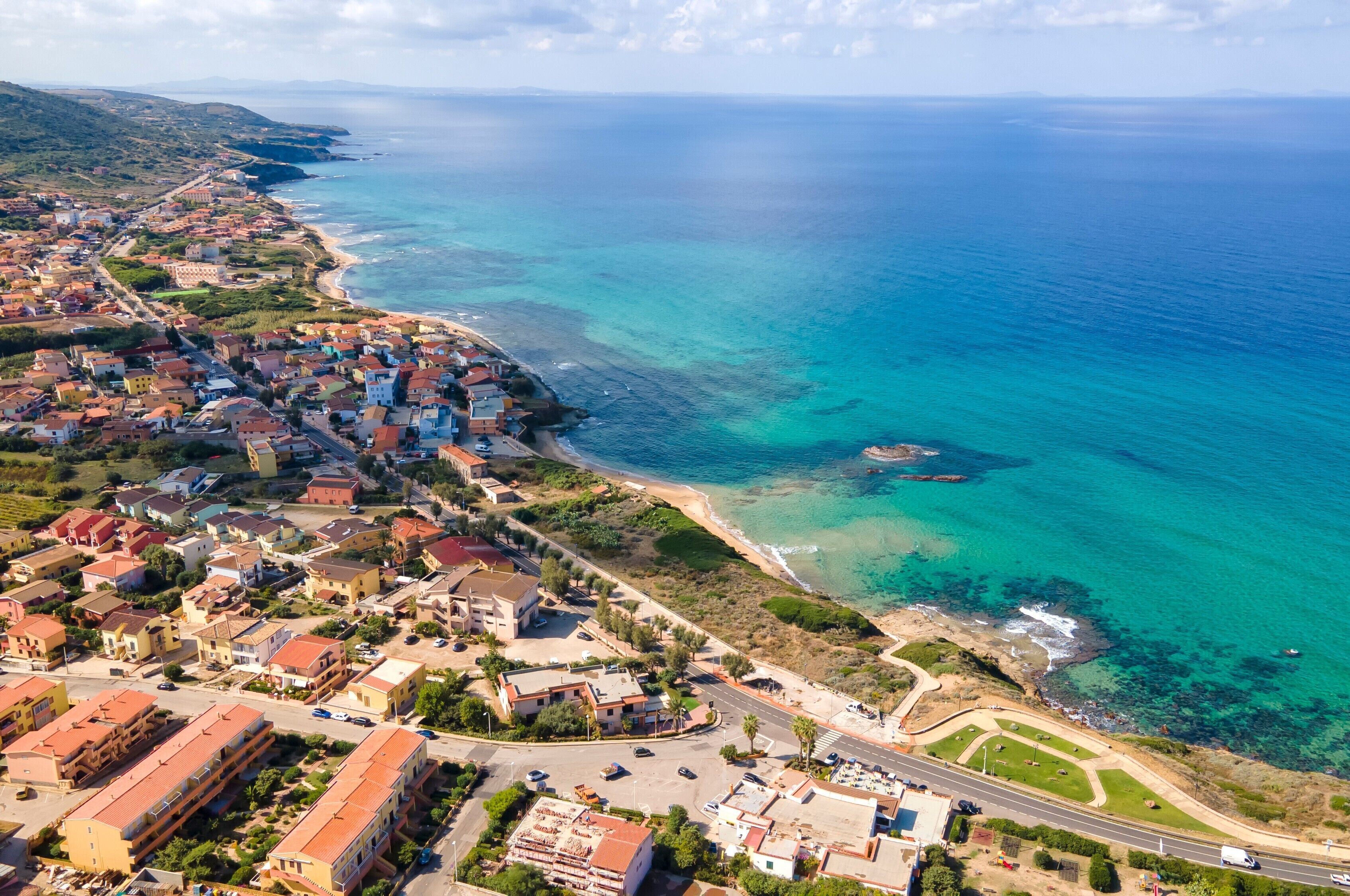 Vista aèria d'una població costanera amb edificis, carreteres i una platja.