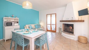 Un coin repas avec une table blanche, des chaises bleues et un meuble blanc contenant un four à micro-ondes.