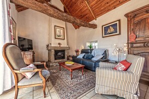 Un salon avec une cheminée, un canapé, un fauteuil et un téléviseur.
