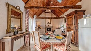 A rustic dining area with wooden beams, a fireplace, and a white refrigerator. - Cottage 'Gîte Calme Avec Jardin Et Terrasse' with Private Terrace, Private Garden and Wi-Fi (Guiclan)