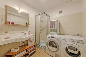 A bathroom with a sink, mirror, shower, and a washing machine. - Cottage 'Gîte Calme Avec Jardin Et Terrasse' with Private Terrace, Private Garden and Wi-Fi (Guiclan)