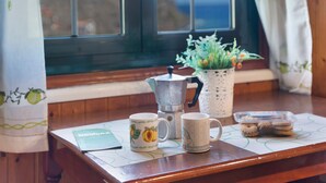 Ein Holztisch mit einer Kaffeekanne, zwei Tassen, einer Topfpflanze und einer Keksdose.