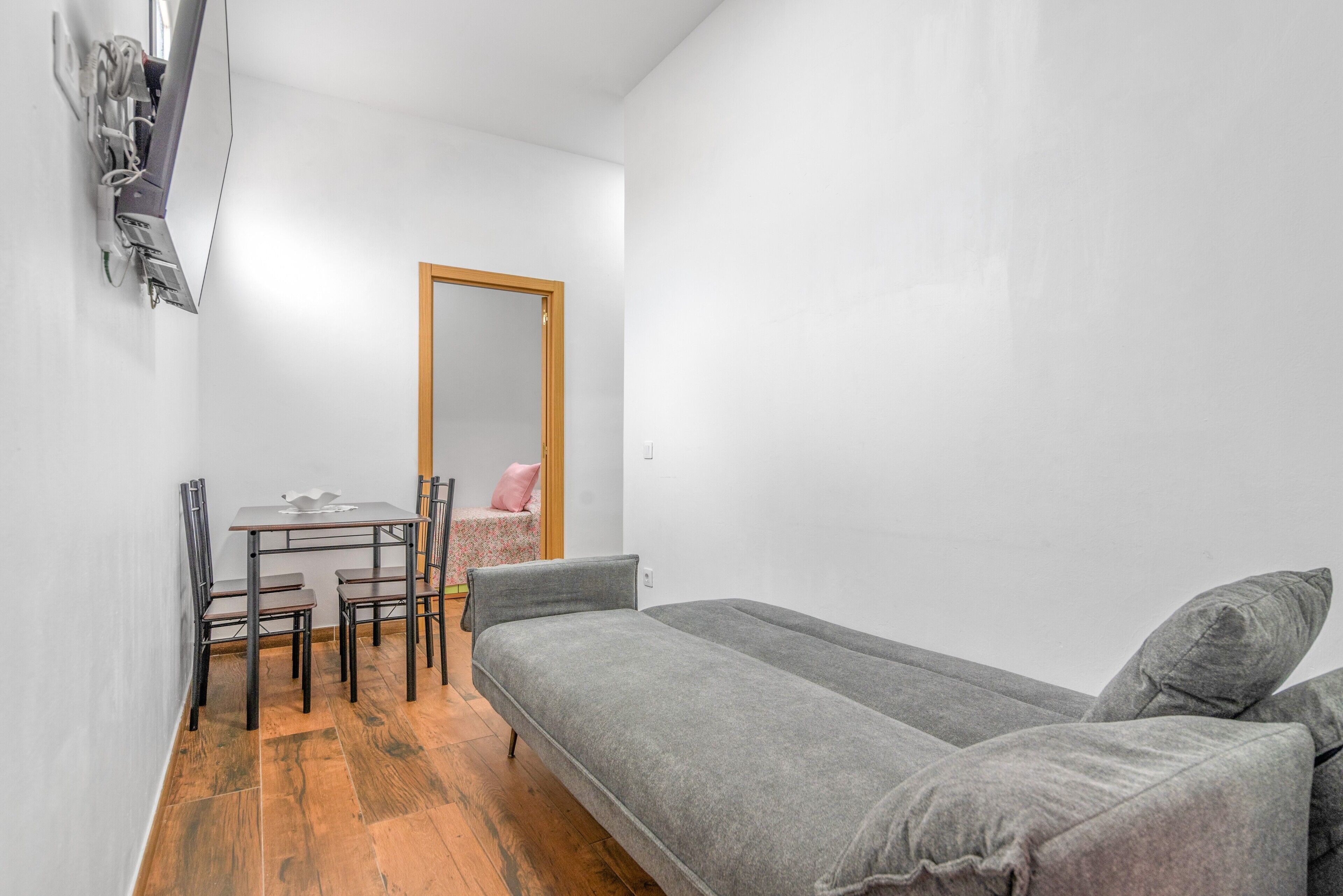 A small, modern room with a bed, a table with chairs, and a mirror on the wall.