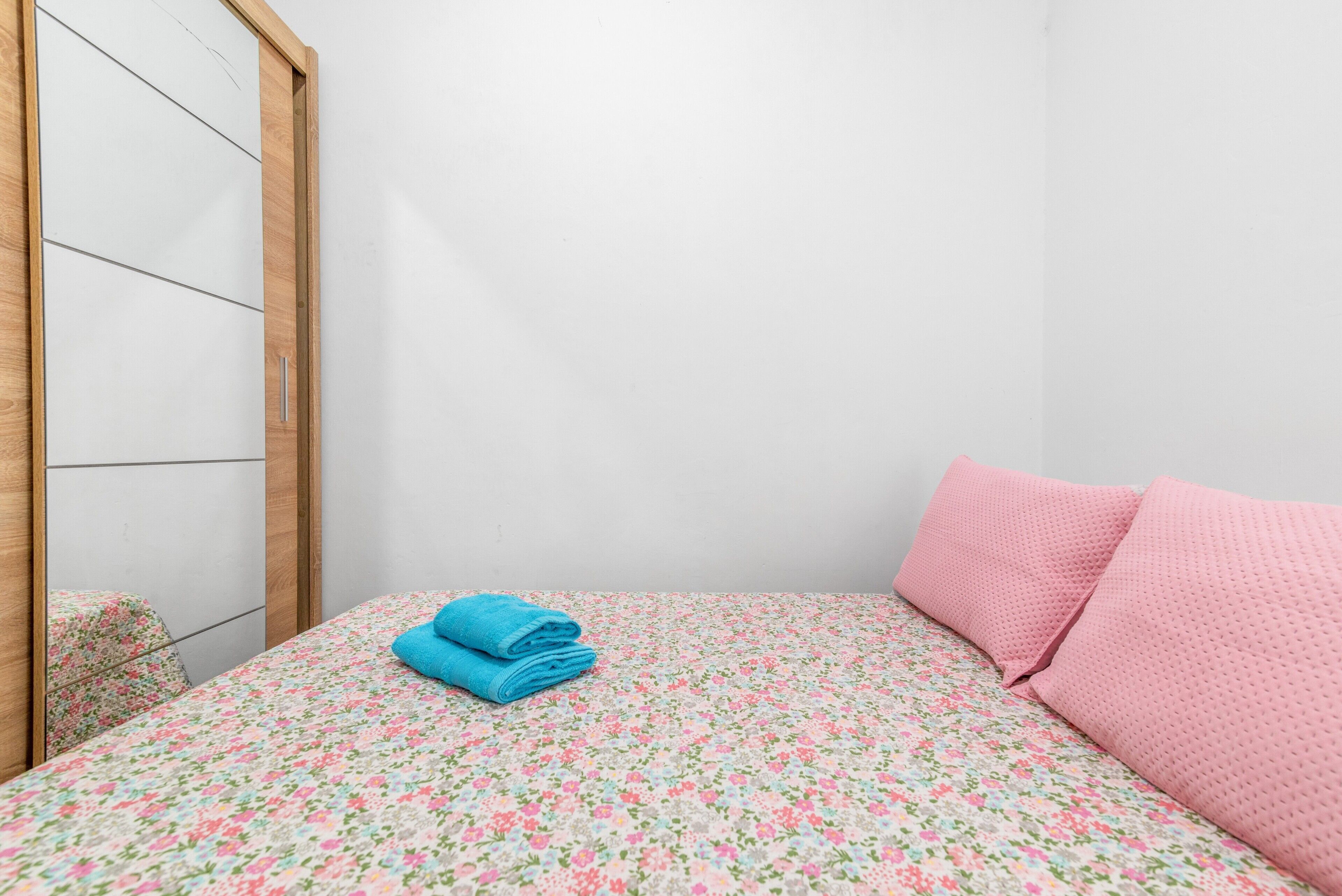 A bedroom with a bed, a wooden wardrobe, and a mirror.