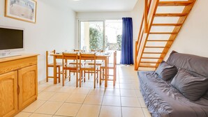 Un espacio moderno de estar con comedor, sofá, televisor y una escalera.