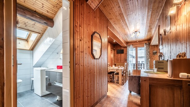 A wooden interior with a kitchen, dining area, and a bathroom with a skylight.