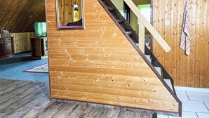A wooden staircase in a room with a sloped ceiling, a small window with a sign, and a television on a stand. - Kranich by Interhome (Lübz)