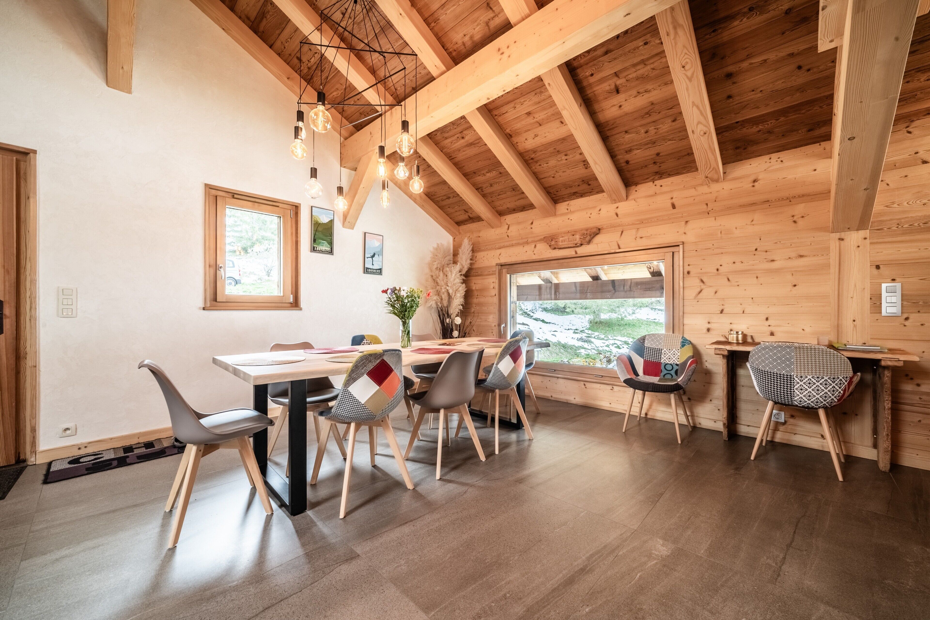 A wooden interior with a dining table, chairs, and a window.