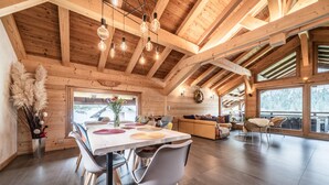 A spacious wooden interior with a dining area, seating, and large windows.