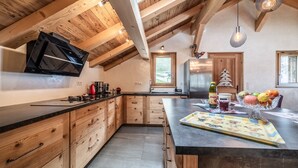 A kitchen with wooden cabinets, a black countertop, a built-in stove, and a hanging light fixture.