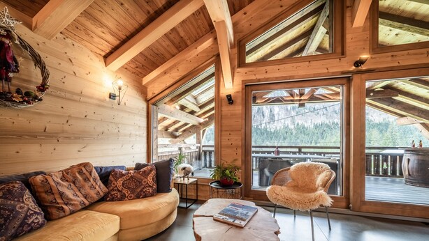 A wooden interior with a sofa, a round wooden table, and a chair.