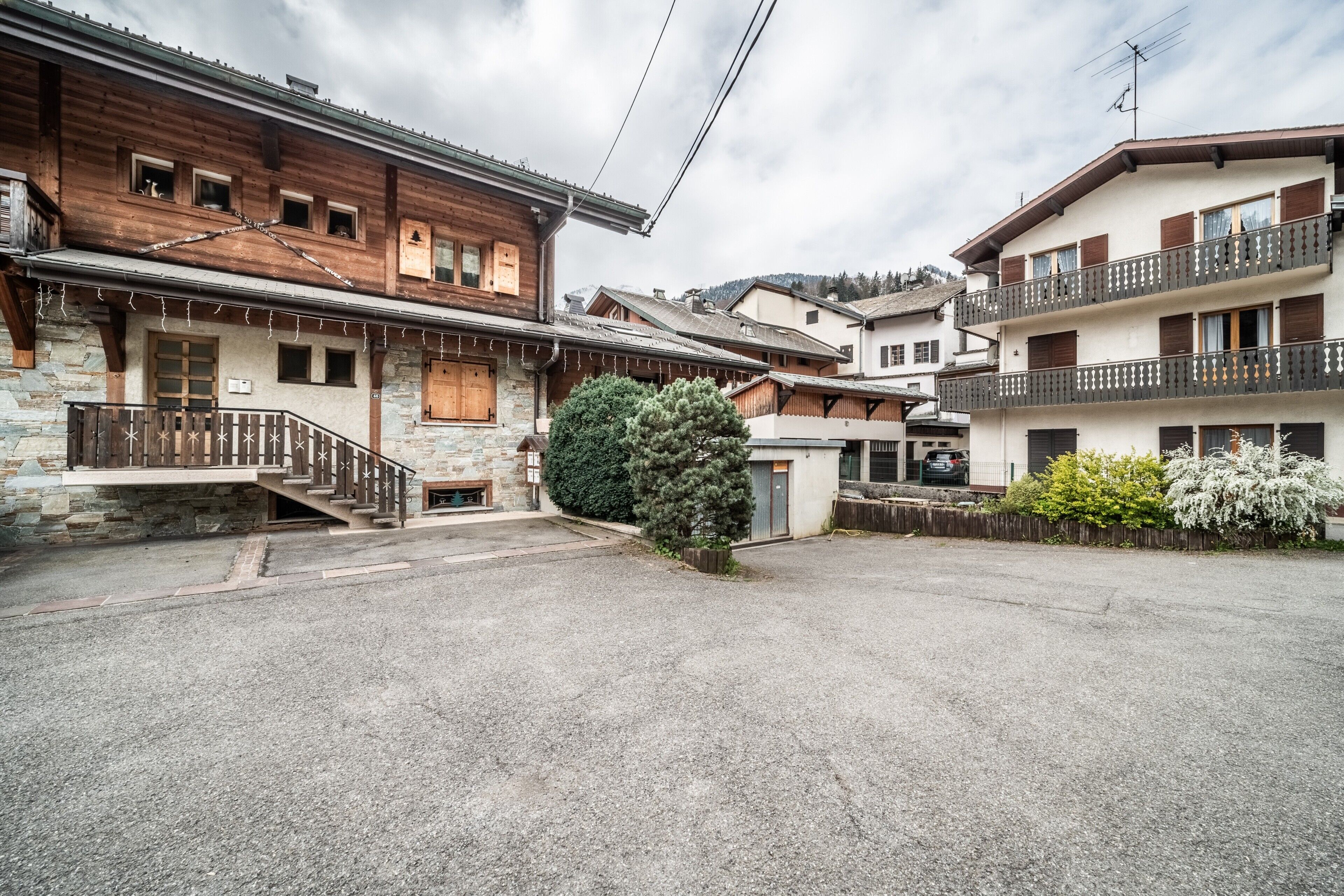 Ein traditionelles Chalet mit Steinaußenwand, Holzbalkonen und einem Kieshof.
