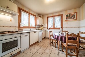 Una cucina con mobili bianchi, un fornello e un tavolo da pranzo con sedie.