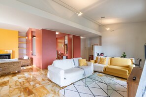 Una sala de estar moderna con un sofá, un sillón amarillo, una chimenea y un comedor.