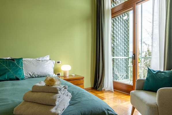 A bedroom with a bed, bedside table, lamp, and a view through a glass door.