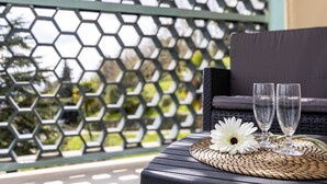 A balcony with a woven table, two glasses, and a white flower. - Room 'Stanza Miele' with Mountain View, Shared Terrace and Wi-Fi (Montevecchia)