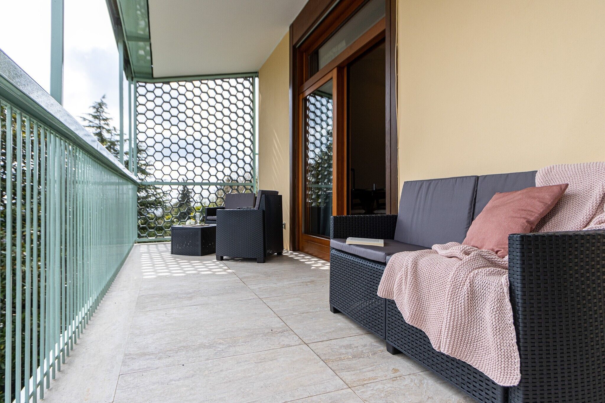 Un balcon avec un canapé en osier, deux fauteuils et une petite table.