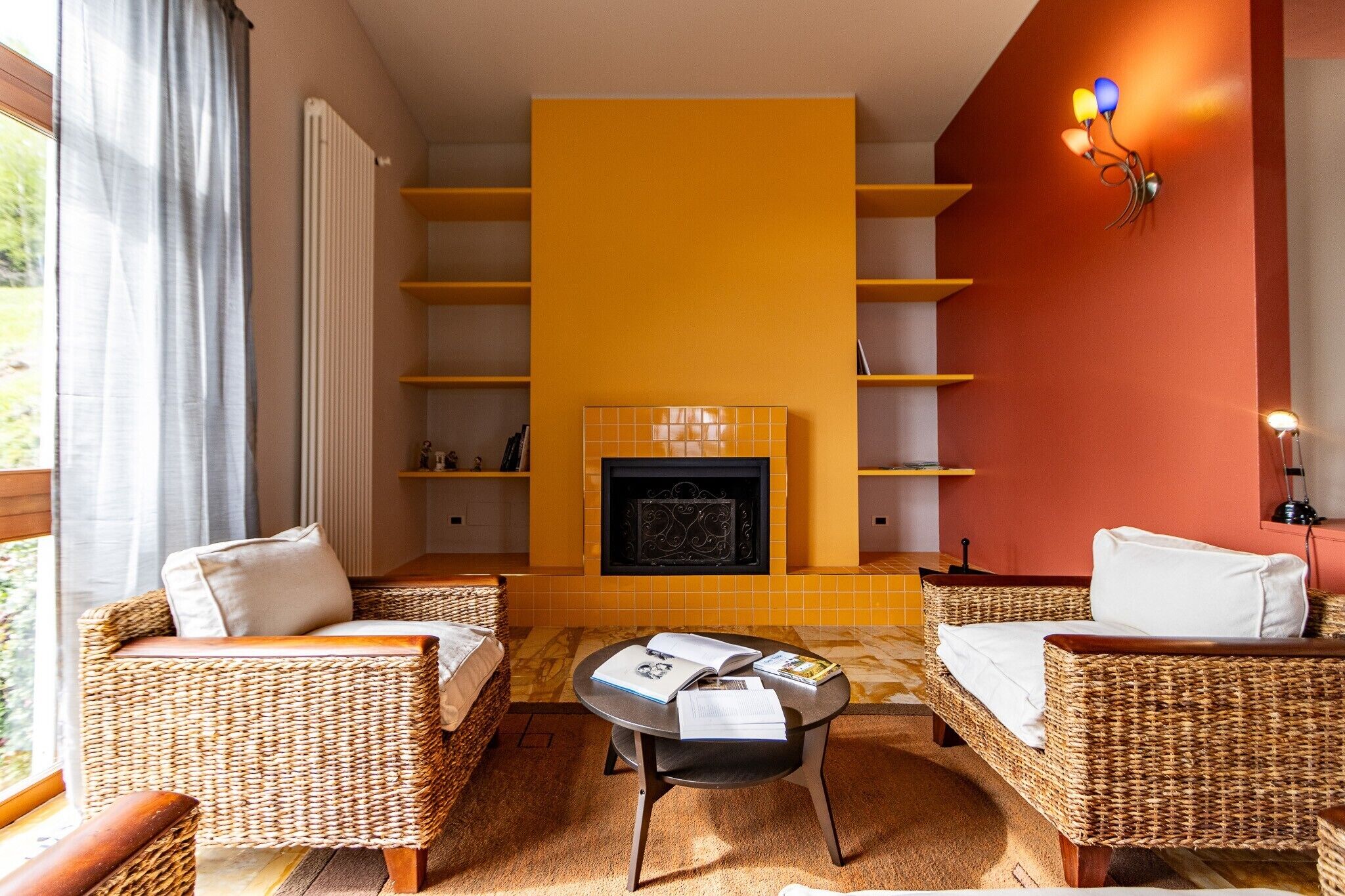 A living room with wicker furniture, a fireplace, and a yellow wall.
