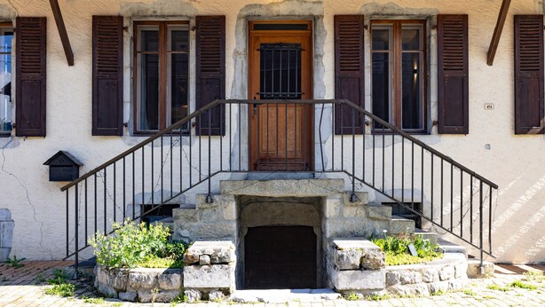 Un edificio con puerta de madera, escalones de piedra y un cartel que dice 'La Fruitiere'.