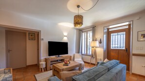 Una sala de estar con televisión, sofá, mesa de centro y una lámpara.
